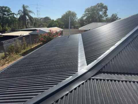 Fresh black corrugated Colorbond and new ridge flashing on a suburban home