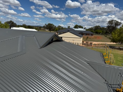 New grey Colorbond roof with new homes and paddocks in the distance